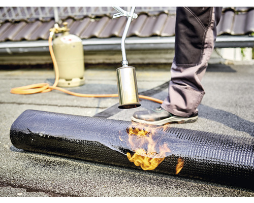 Dakdekker last met een gasbrander een dakbedekking op een dak