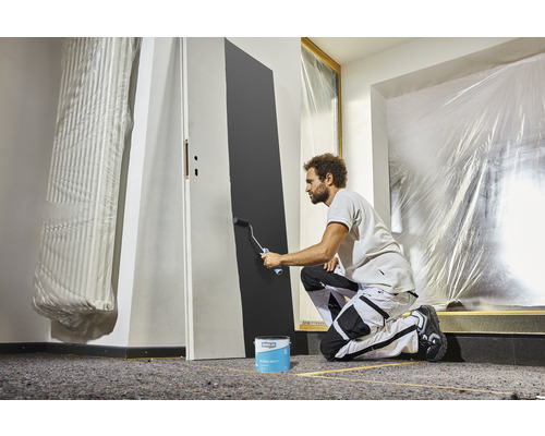 Man schildert een deur met een verfroller en verf