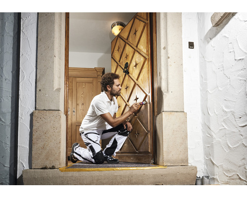 Ambachtsman schildert een houten deur met sterpatroon en ornamenten met een penseel.