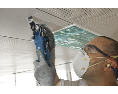 Vakman werkt met een multifunctioneel gereedschap aan een plafondplaat