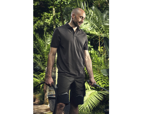 Man met poloshirt en werkshorts, die planten in de tuin water geeft