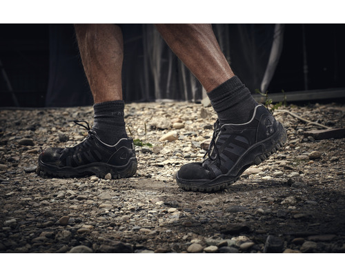 Persoon met werkschoenen op een steenachtige ondergrond
