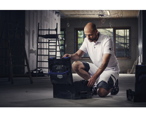 Ambachtsman met geopende gereedschapskist op een bouwplaats