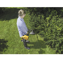 Vrouw werkt met een gele grastrimmer in de tuin.
