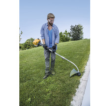 Een man trimt gazon met een grastrimmer in een tuin.