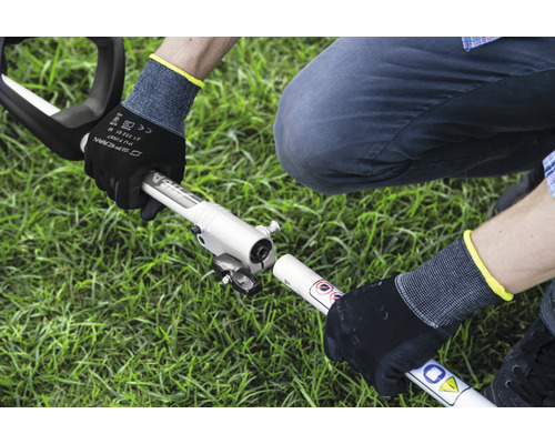 Montage van een motorzeis door een persoon met werkhandschoenen in de tuin