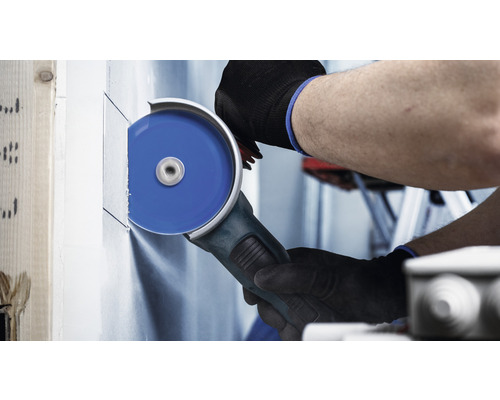 Een persoon snijdt met een haakse slijper een gipsplatenwand.