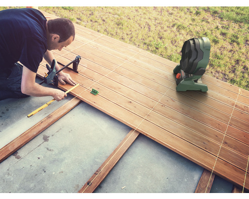 Man legt een houten terras aan met gereedschap en een ventilator