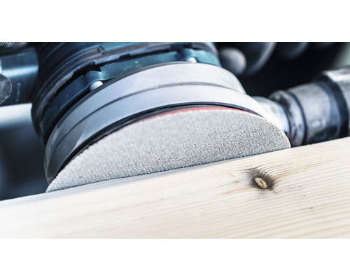 Detailopname van een schuurmachine die een stuk hout bewerkt.