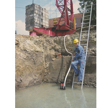 Bouwput met water, dompelpomp, arbeider op ladder en kraan op de achtergrond