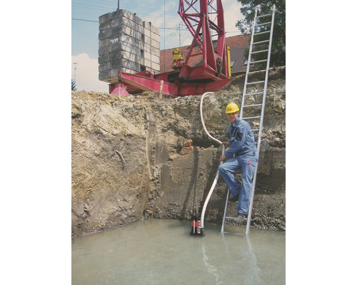 Bouwput met water, dompelpomp, arbeider op ladder en kraan op de achtergrond