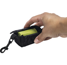 Hand houdt een zwarte poepzakjeshouder vast met karabijnhaak en een rol hondenpoepzakjes.