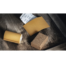 Schuurpapierrol, schuurpapiervel en schuurkurk op een houten ondergrond