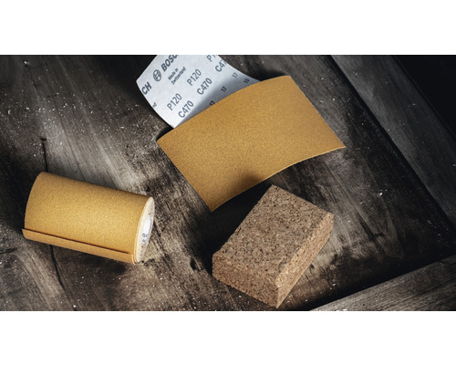 Schuurpapierrol, schuurpapiervel en schuurkurk op een houten ondergrond