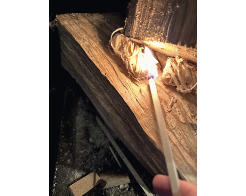 Een stuk hout wordt aangestoken met een lucifer.