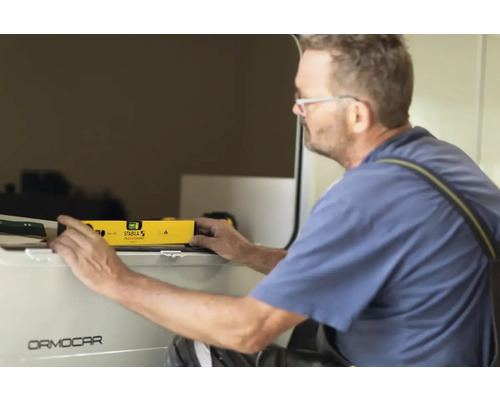 Een man gebruikt een waterpas om een oppervlak uit te lijnen.