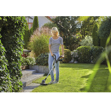 Vrouw gebruikt een grastrimmer in de tuin voor gazononderhoud.