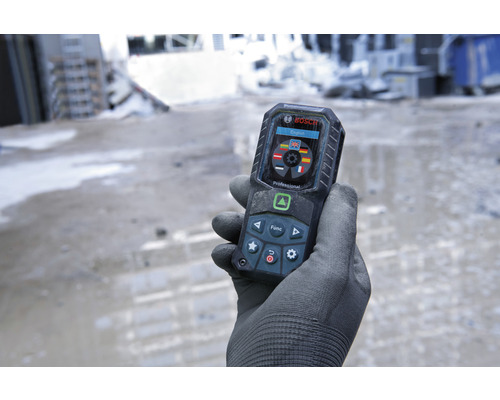 Een hand met handschoen houdt een digitale afstandsmeter van Bosch vast.