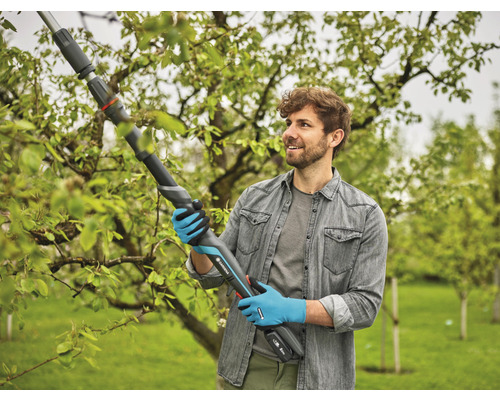 Man gebruikt een Gardena accu-takkenschaar om takken in de tuin te snoeien.