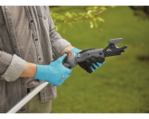 Een persoon bedient een takkenschaar aan een stang met tuinhandschoenen.