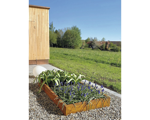 Metalen plantenbak met bloeiende planten en een decoratieve bol in de tuin