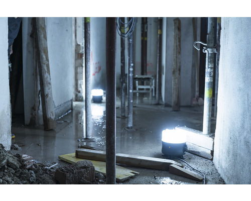 Bouwplaats met bouwlampen, stutten en bouwmaterialen in een vochtige kelder