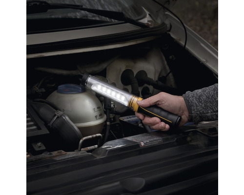 Iemand houdt een led-werklamp onder de motorkap van een auto