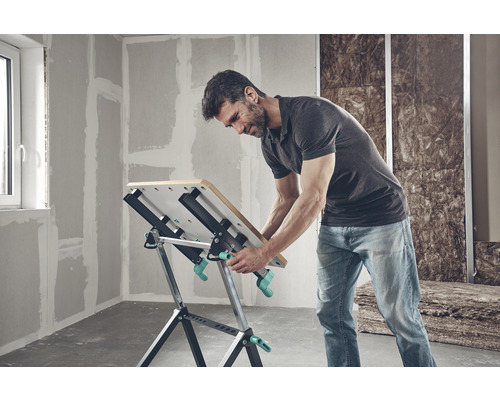 Man werkt aan een Wolfcraft werkbank in een niet-gerenoveerde kamer.