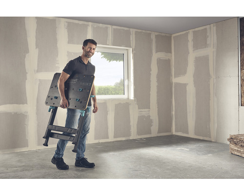 Man draagt een Wolfcraft Master 650 werkbank in een kamer met gipsplaten muren