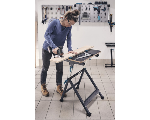 Vrouw werkt met decoupeerzaag aan een werkbank in een werkplaats.