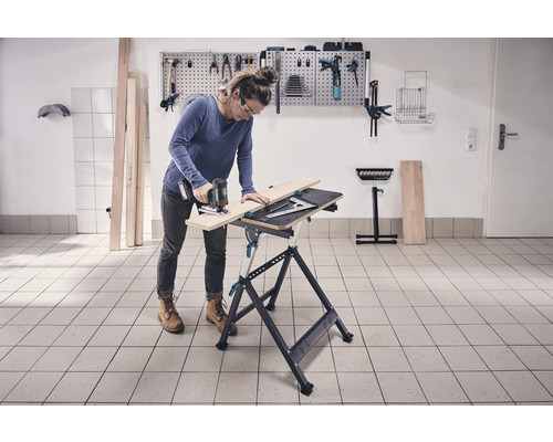 Vrouw zaagt hout op een werkbank met een decoupeerzaag in een werkplaats