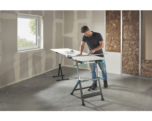 Man snijdt gipsplaat op een Wolfcraft werktafel in een ruwbouw.