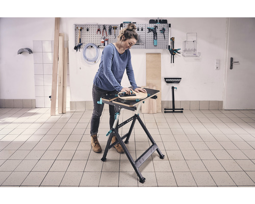 Vrouw werkt aan een werkbank met gereedschap aan de muur