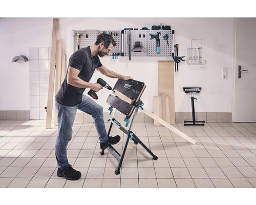 Een man boort een werkstuk met een accuboormachine op een Wolfcraft Master 600 werkbank.