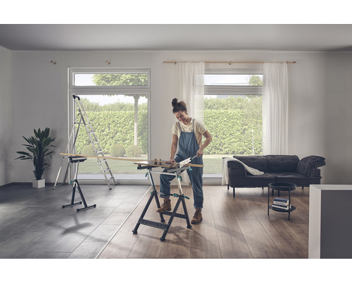 Een vrouw zaagt hout op een werkbank in een lichte kamer