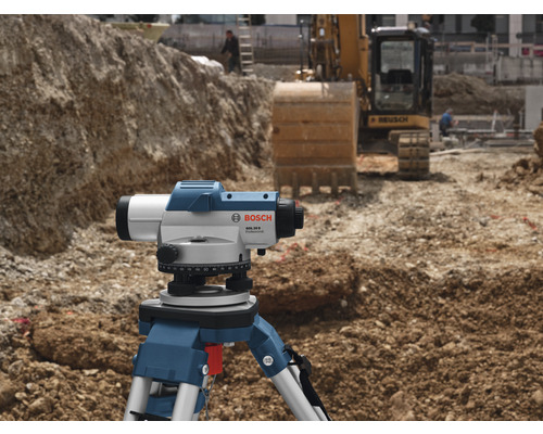 Bosch logo. Bouwplaats met waterpasinstrument op statief en graafmachine op de achtergrond.