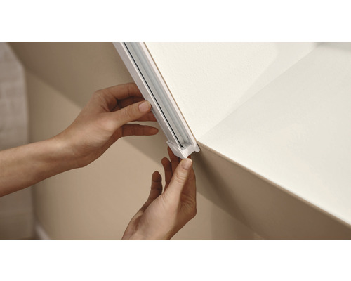 Installatie van een gordijnrail aan het plafond door een persoon.