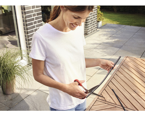 Vrouw knipt kantenband met een schaar op een houten tafel buiten
