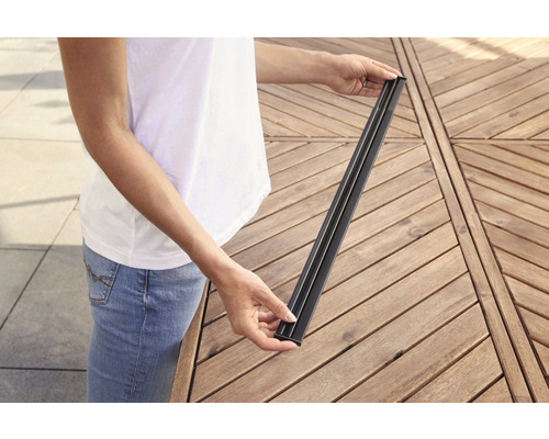 Een persoon houdt een terrasplank van composietmateriaal in zijn handen.