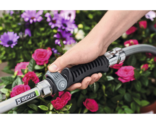 Een hand houdt een tuinslang met GEKA-koppeling vast voor bloemen