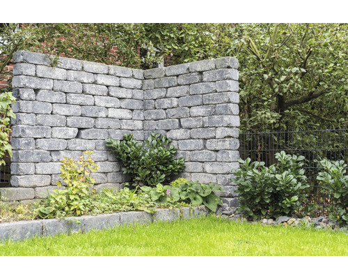 Grijze tuinmuur met beplanting in de tuin