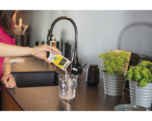 Vrouw giet reinigingsmiddel van Kärcher in een maatbeker met water.