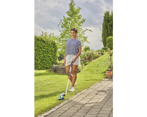 Vrouw gebruikt gazontrimmer in de tuin