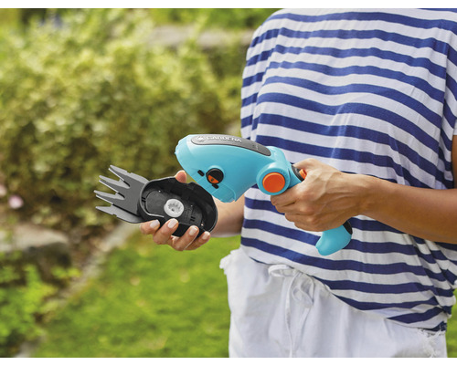 Een persoon houdt een Gardena draadloze grasschaar vast met een verwisselbare meskop.