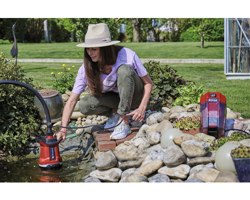 Vrouw bedient een vijverpomp in een tuinvijver.