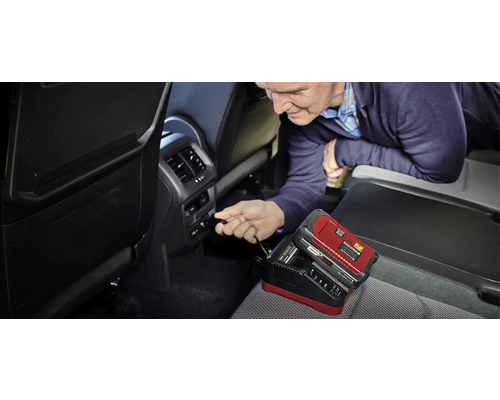 Man sluit een acculader aan in de auto