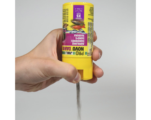 Hand houdt voer JBL Novo Danio voor kleine vissen vast