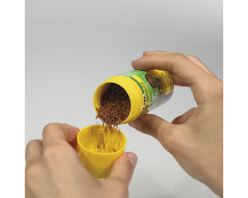 Handen vullen JBL insectenvoer in een gele deksel