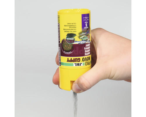 JBL Novo Guppy visvoer blik wordt met de hand vastgehouden en er stroomt visvoer uit