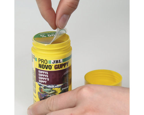 De foto toont hoe een verpakking JBL Pro Novo Guppy visvoer wordt geopend.